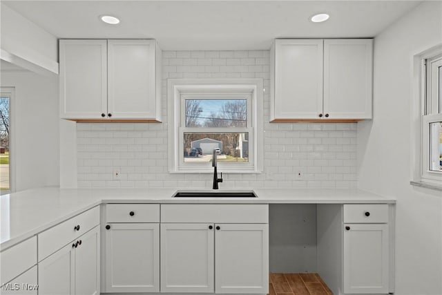 kitchen featuring white cabinets, plenty of natural light, light countertops, and a sink