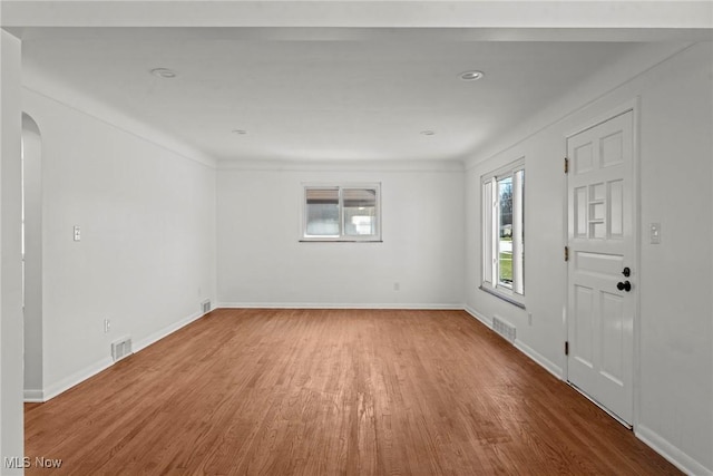 entryway featuring arched walkways, visible vents, baseboards, and wood finished floors