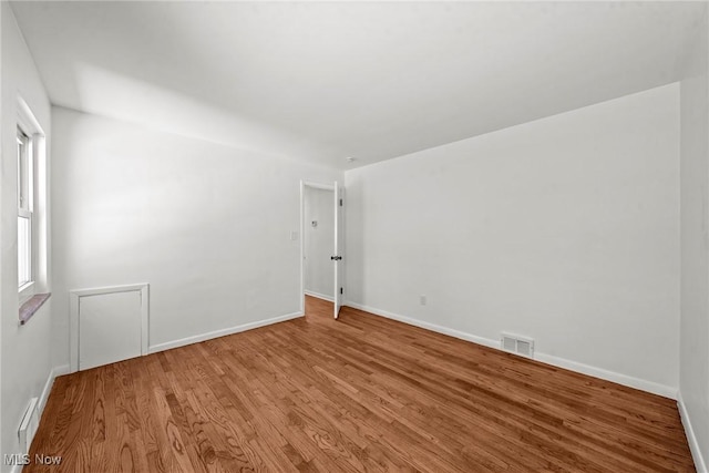 unfurnished room with visible vents, baseboards, and wood finished floors