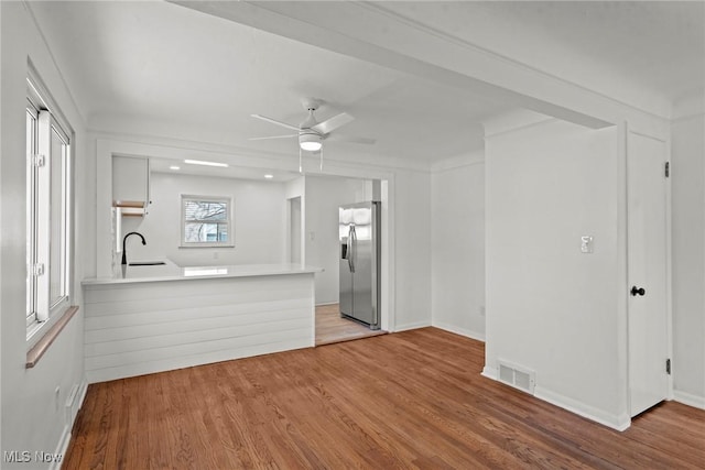 unfurnished living room featuring visible vents, baseboards, a sink, ceiling fan, and wood finished floors