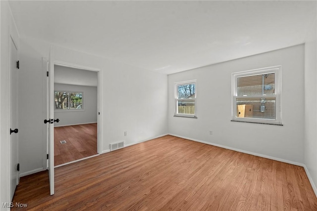 unfurnished room featuring visible vents, baseboards, and wood finished floors