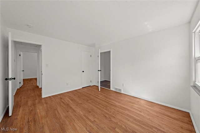 unfurnished bedroom with wood finished floors, baseboards, and visible vents