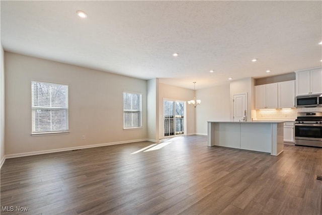 kitchen featuring stainless steel appliances, tasteful backsplash, a notable chandelier, and dark wood-style floors
