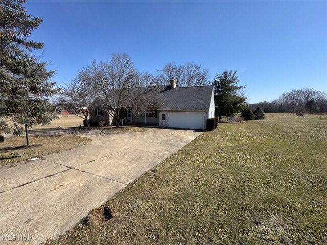 view of front of property featuring a front yard, an attached garage, driveway, and a chimney