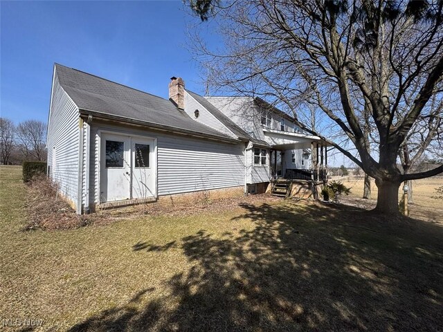back of property with a lawn and a chimney