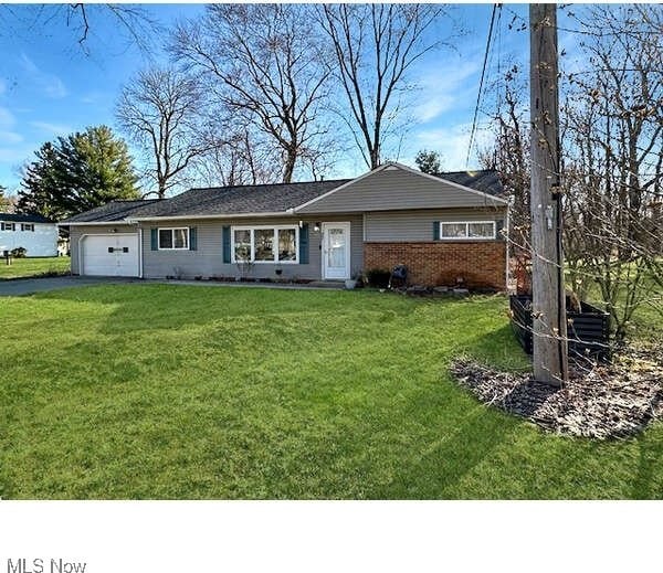 single story home featuring brick siding, an attached garage, driveway, and a front lawn