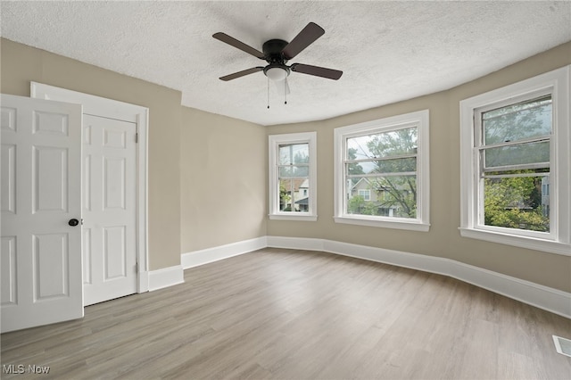 1344 E 112th St, Cleveland, OH 44106 - empty room featuring wood finished floors, a healthy amount of sunlight, baseboards, and a textured ceiling