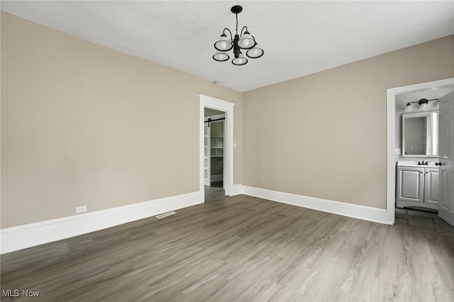 1344 E 112th St, Cleveland, OH 44106 - empty room featuring a notable chandelier, wood finished floors, baseboards, and a sink
