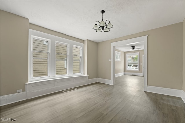 1344 E 112th St, Cleveland, OH 44106 - unfurnished dining area featuring visible vents, baseboards, ceiling fan with notable chandelier, wood finished floors, and a textured ceiling
