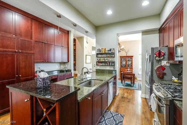 1581 E 118th St, Cleveland, OH 44106 - kitchen with a sink, dark stone countertops, reddish brown cabinets, light wood-style floors, and appliances with stainless steel finishes