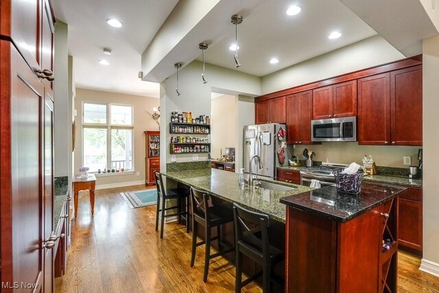 1581 E 118th St, Cleveland, OH 44106 - kitchen featuring dark brown cabinets, a kitchen bar, appliances with stainless steel finishes, wood finished floors, and a sink