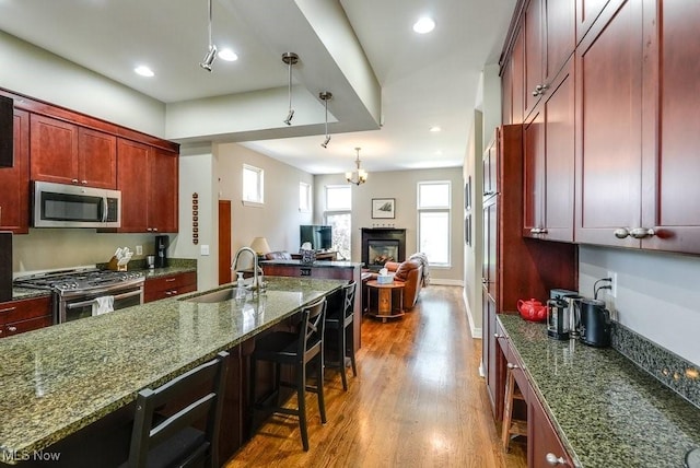 1581 E 118th St, Cleveland, OH 44106 - kitchen featuring a sink, dark stone countertops, wood finished floors, stainless steel appliances, and reddish brown cabinets