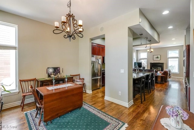 1581 E 118th St, Cleveland, OH 44106 - dining room featuring a notable chandelier, a glass covered fireplace, dark wood-type flooring, and baseboards