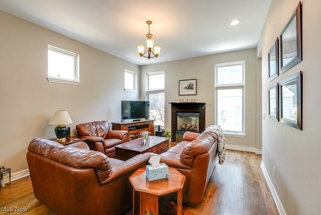 1581 E 118th St, Cleveland, OH 44106 - living room with a glass covered fireplace, an inviting chandelier, baseboards, and wood finished floors