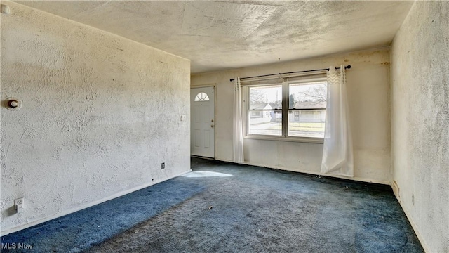 carpeted spare room with a textured wall