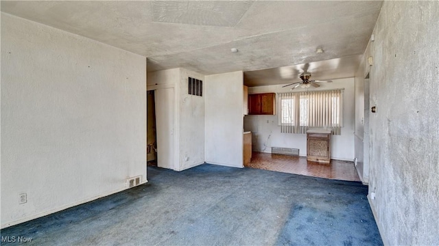 unfurnished living room featuring visible vents, a ceiling fan, and a textured wall