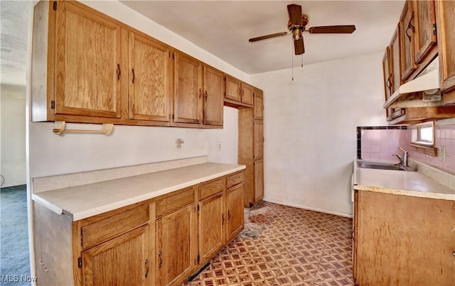 kitchen featuring ceiling fan, light countertops, decorative backsplash, brown cabinetry, and a sink