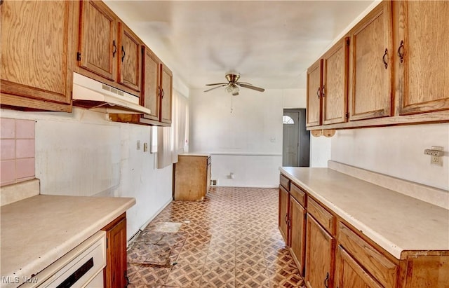 kitchen with under cabinet range hood, light countertops, brown cabinetry, and ceiling fan