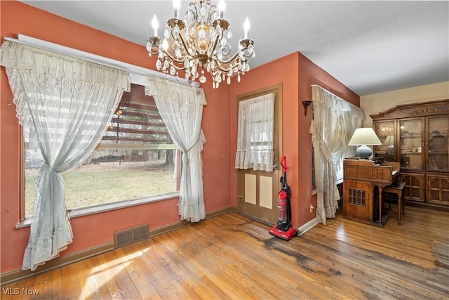 dining room featuring an inviting chandelier, hardwood / wood-style flooring, visible vents, and a wealth of natural light