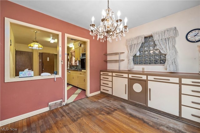kitchen with visible vents, baseboards, a chandelier, decorative light fixtures, and hardwood / wood-style flooring