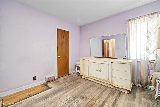 bedroom featuring multiple windows, wood finished floors, and baseboards