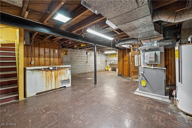 unfinished below grade area with water heater, heating unit, tile patterned floors, and stairs