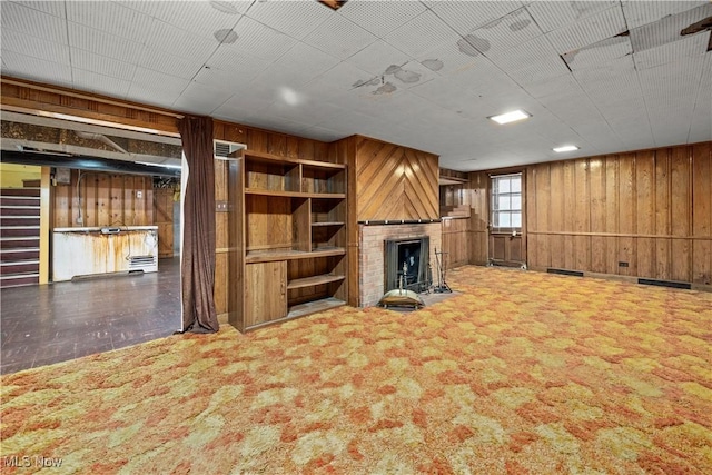below grade area featuring wooden walls, built in features, a fireplace, and carpet floors