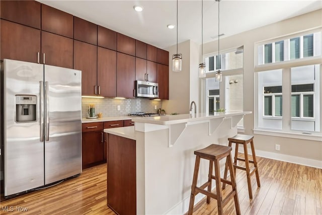 1228 W 74th St, Cleveland, OH 44102 - kitchen featuring backsplash, a kitchen bar, light countertops, light wood-style flooring, and stainless steel appliances