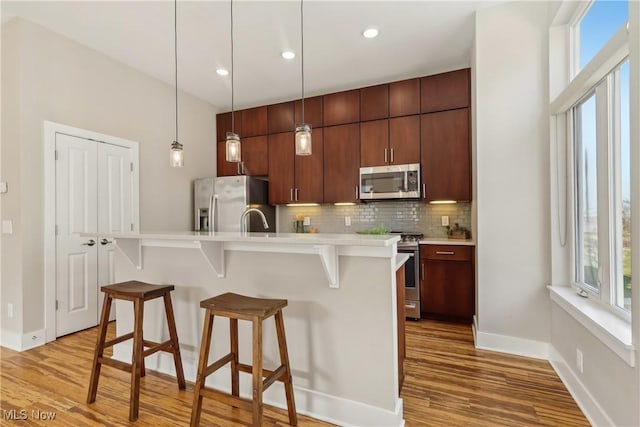 1228 W 74th St, Cleveland, OH 44102 - kitchen with backsplash, a kitchen bar, light wood-type flooring, light countertops, and stainless steel appliances