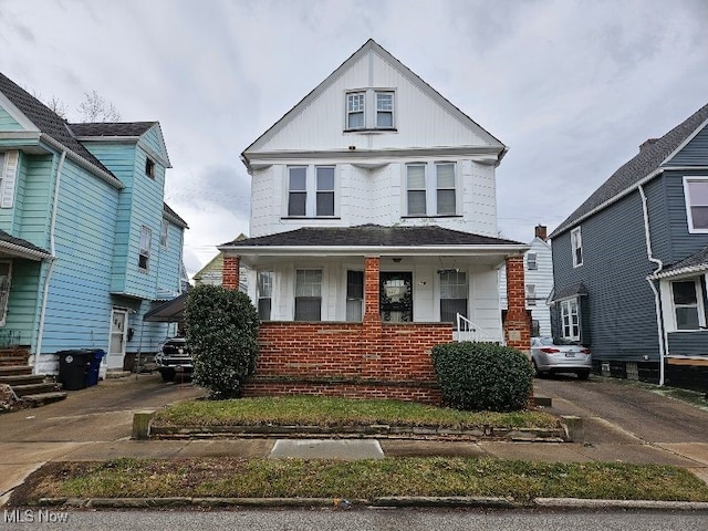 view of front facade with brick siding, a porch, and driveway