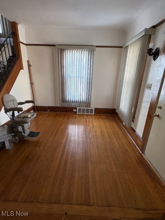 unfurnished living room featuring visible vents, baseboards, and hardwood / wood-style floors