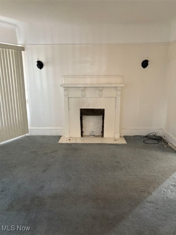 unfurnished living room featuring carpet flooring, a fireplace, and baseboards