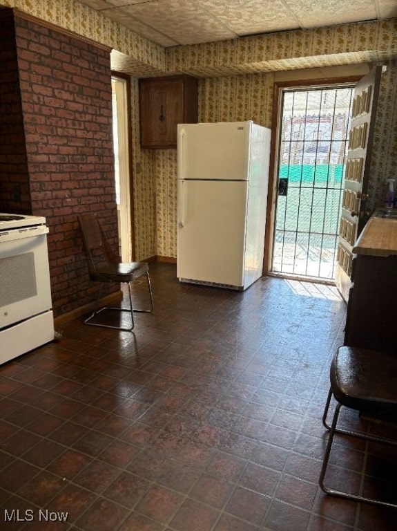 kitchen with white appliances, wallpapered walls, and baseboards