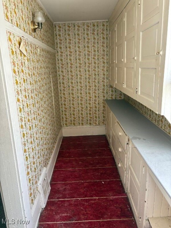 interior space featuring visible vents, wallpapered walls, baseboards, and dark wood-style flooring