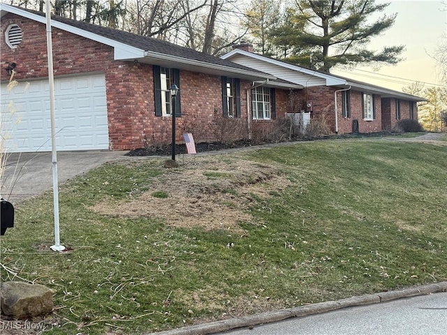106 Wildwood Dr, Marietta, OH 45750 - view of side of home with a garage, driveway, brick siding, and a lawn