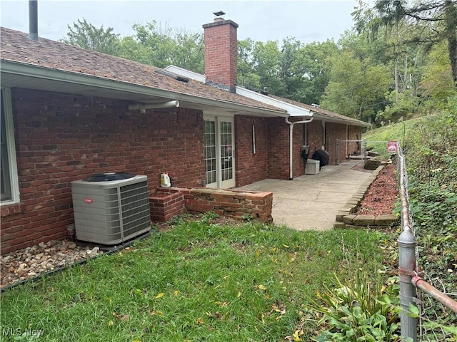 106 Wildwood Dr, Marietta, OH 45750 - back of property with brick siding, central AC unit, a chimney, and a patio