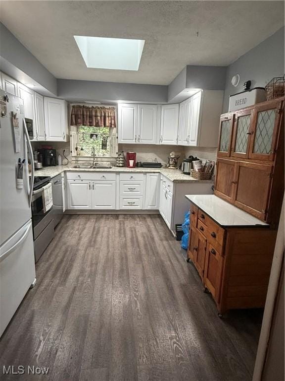 106 Wildwood Dr, Marietta, OH 45750 - kitchen featuring dark wood finished floors, a skylight, freestanding refrigerator, stainless steel range, and a sink
