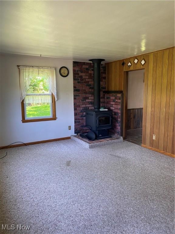 30173 Georgetown Rd, Salem, OH 44460 - unfurnished living room with a wood stove, baseboards, carpet floors, and wood walls