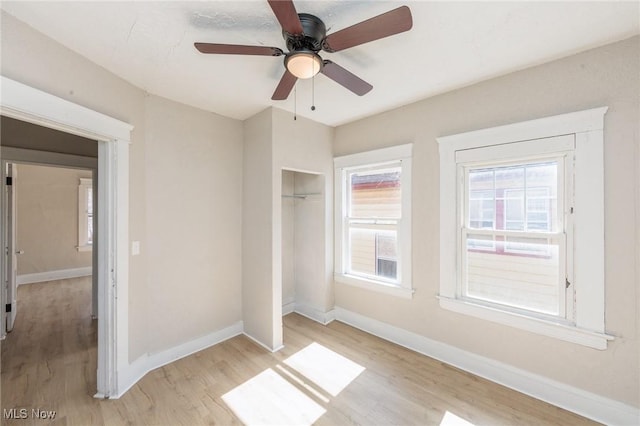 unfurnished bedroom with a ceiling fan, baseboards, light wood-type flooring, and a closet