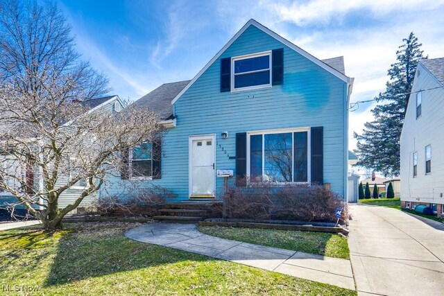 view of front of house featuring a front yard and a shingled roof