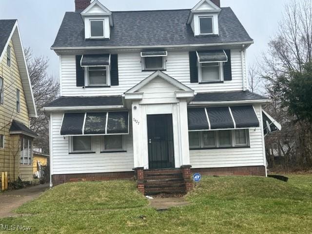 view of front of home with entry steps, a front yard, a chimney, and a shingled roof