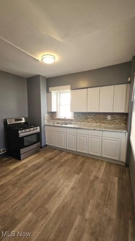 kitchen with dark wood finished floors, gas range, white cabinets, and tasteful backsplash