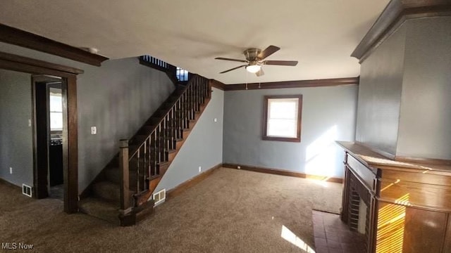 unfurnished living room featuring stairway, a ceiling fan, visible vents, and carpet floors