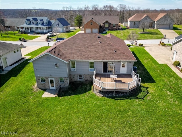 rear view of house featuring a deck, a lawn, and a residential view