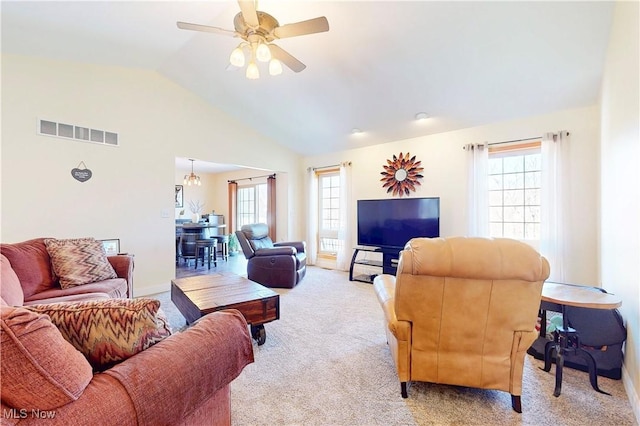 living area with light carpet, visible vents, plenty of natural light, and vaulted ceiling