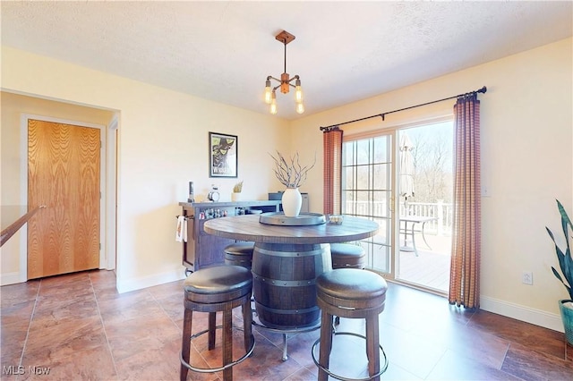 dining room featuring an inviting chandelier, baseboards, and a textured ceiling