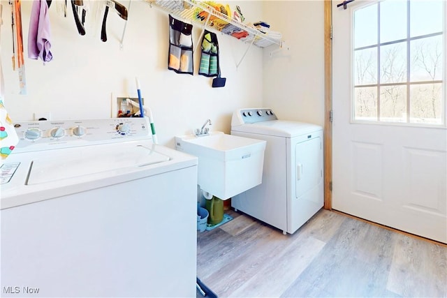 laundry area with washer and clothes dryer, laundry area, light wood finished floors, and a sink