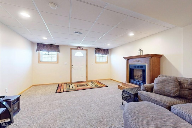 carpeted living room with a drop ceiling, baseboards, visible vents, and a wealth of natural light