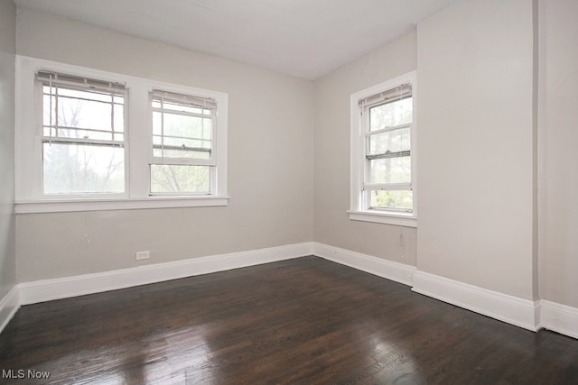 spare room featuring dark wood finished floors and baseboards