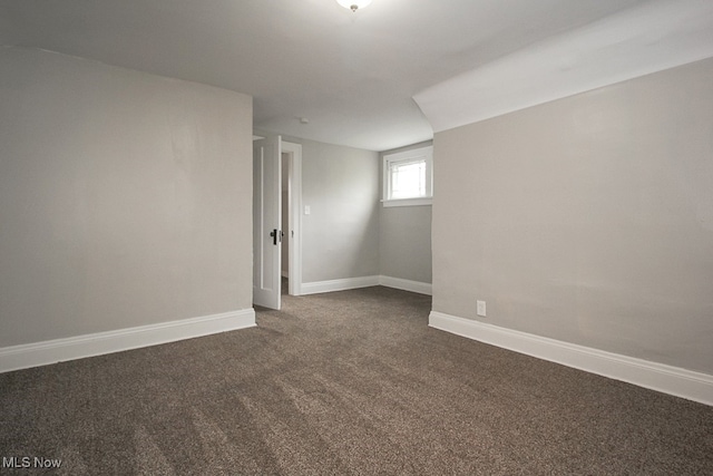 spare room with dark carpet and baseboards